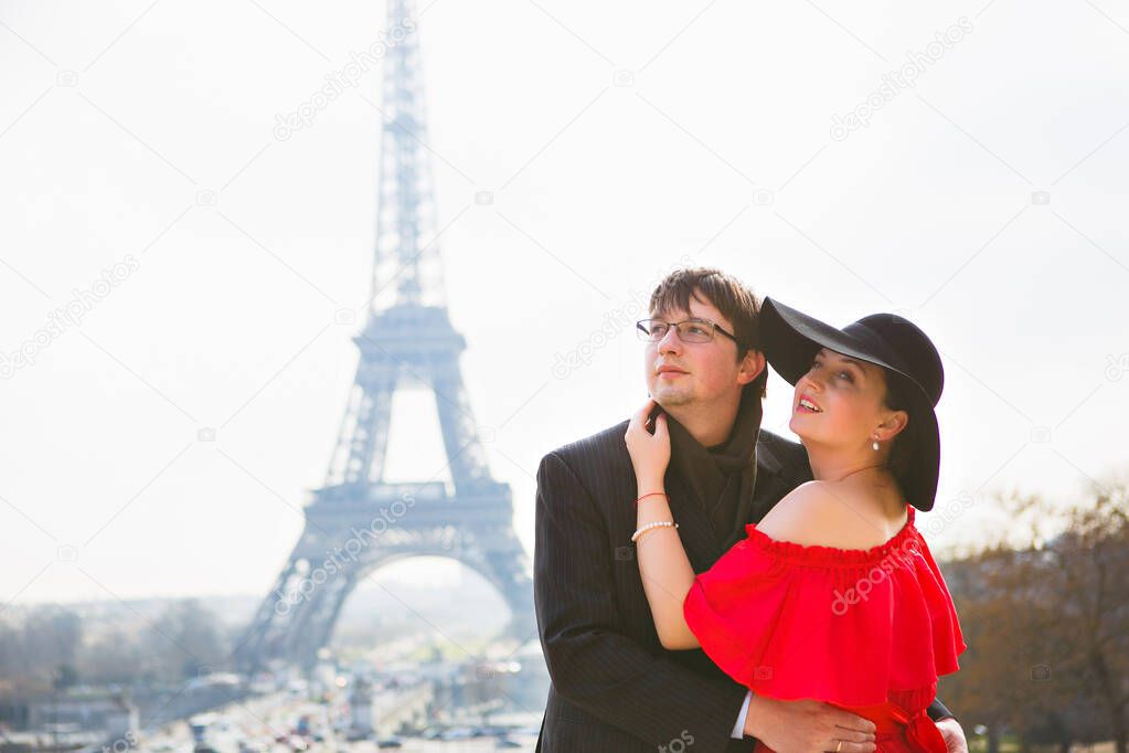 man and woman in red dress and hat on Eiffel tower in Paris. symbol of France.