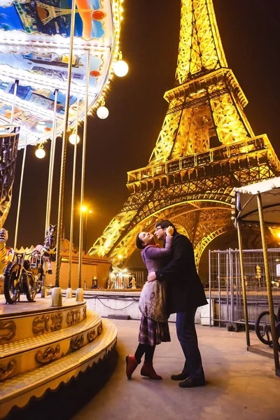 Amantes cerca de la Torre Eiffel y la noche de carruseles en París . — Foto de Stock