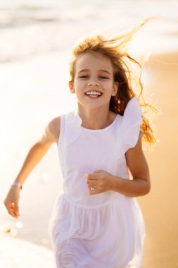 Kız büyük dalgalar ve güçlü rüzgarlarla deniz kıyısında yürüyor ve eğleniyor..