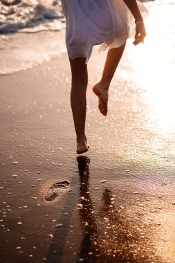Küçük ayaklar denizin kumlu sahillerinde ayak izleri bırakır. Sahilde yürüyor.. 