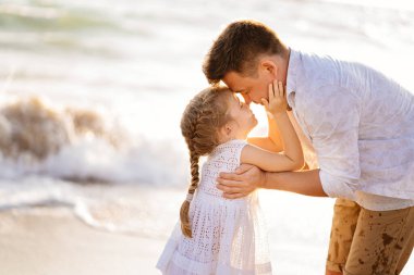 Öptüm. Baba ve kızı rüzgarlı bir havada deniz kıyısında yürüyorlar. eğlenceli aile.