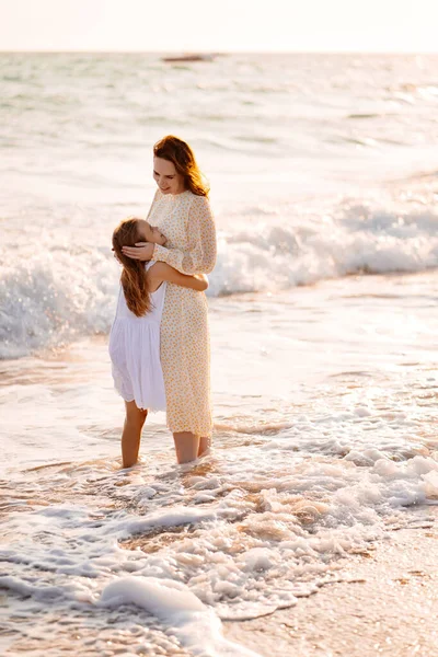 Zabawy mama i dziecko spacerujące po plaży z dużymi falami w wietrzną pogodę. szczęśliwa rodzina — Zdjęcie stockowe