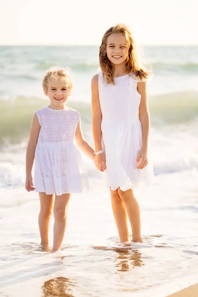 Дети, девочки, гуляющие по пляжу с большими волнами в ветреную погоду. Отдых на море . — стоковое фото