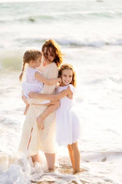 Mama i dzieci spacerujące po plaży morskiej z dużymi falami przy wietrznej pogodzie. szczęśliwa rodzina — Zdjęcie stockowe