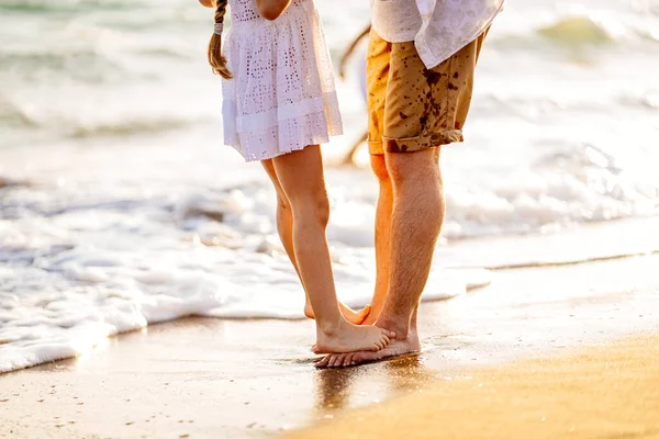 Pieds de papa et fille se tiennent sur la plage de sable fin. vacances en famille en mer . — Photo