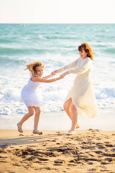 Мама и ребенок гуляют по морскому пляжу с большими волнами в ветреную погоду. счастливая семья — стоковое фото