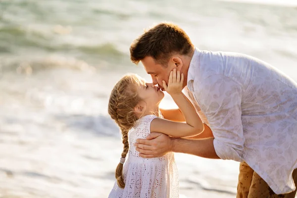 Un beso. padre con hija caminando a lo largo de la orilla del mar en tiempo ventoso. familia divertida . —  Fotos de Stock