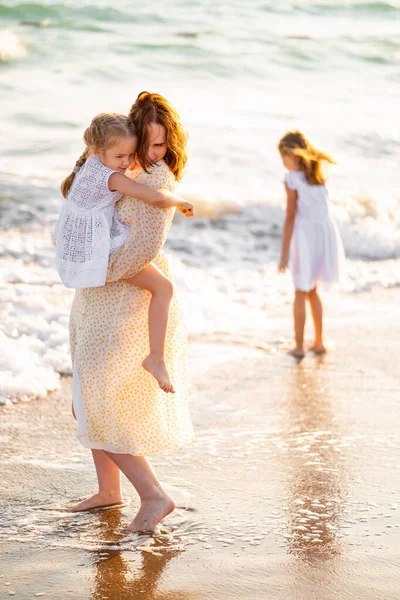 Мама и дети гуляют по морскому пляжу с большими волнами в ветреную погоду. счастливая семья — стоковое фото