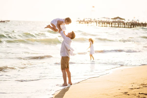 Pappa med döttrar som vandrar längs stranden i blåsigt väder. rolig familj. — Stockfoto