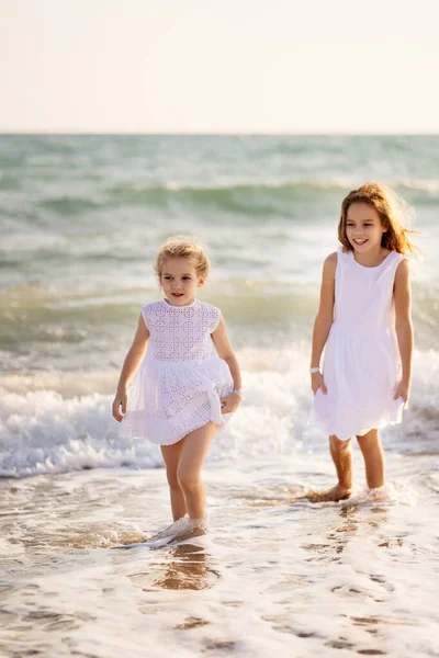 Kinderen, meisjes lopen op het strand met grote golven bij winderig weer. vakantie naar zee. — Stockfoto