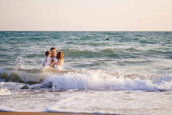 Nassen Vater und Töchter schwimmen im Meer in Kleidung, spielen und Spaß haben. — Stockfoto