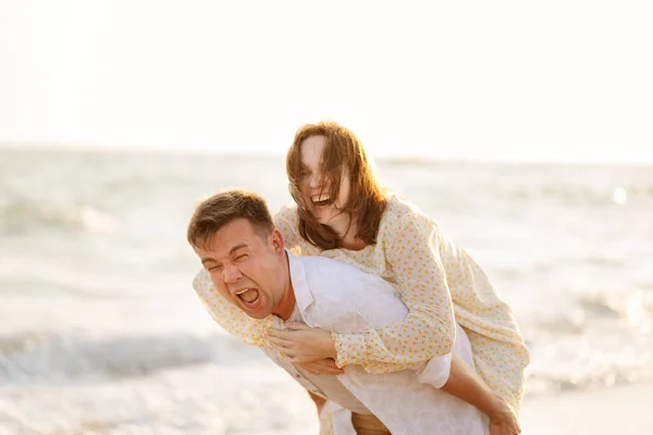 Funny husband and wife on beach. man cannot raise woman, she weighs lot. — Stock Photo, Image