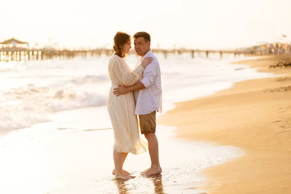 Çift, kumlu sahilde kıyı şeridinde duruyor. Romantik ilişki, birlikte seyahat.. — Stok fotoğraf