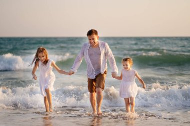 ıslak baba ve kızları elbiseleriyle denizde yüzüyor, oynuyorlar ve eğleniyorlar..