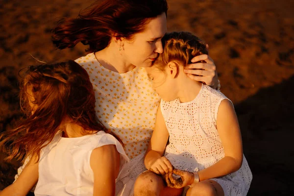 Mutter mit Kindern auf Sand sitzend, Strand am Meer. Beziehung Eltern zu Kindern. — Stockfoto