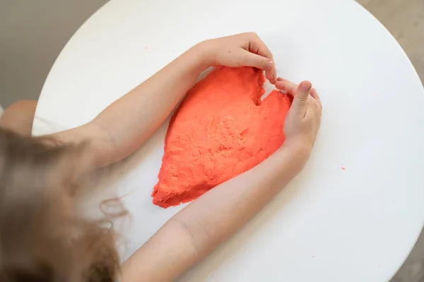 Руки маленькой девочки сделать сердце из кинетического песка. Развитие мелкой моторики — стоковое фото