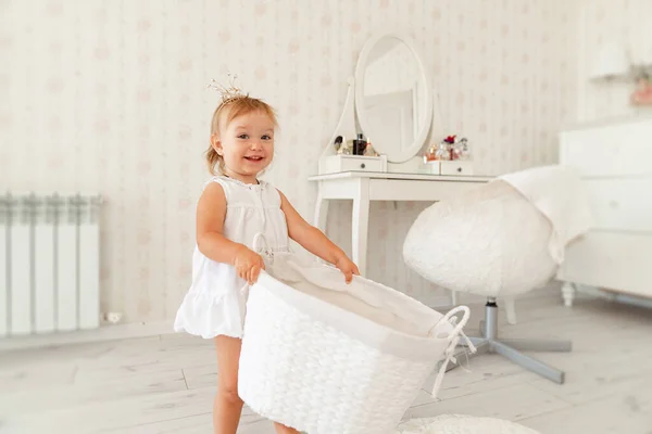 Niño, niña jugando con una cesta blanca para juguetes. feliz infancia . — Foto de Stock