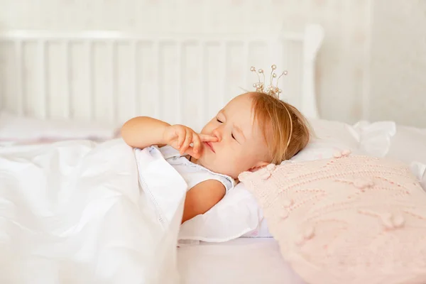 Niña durmiendo en la cama en el dormitorio con corona. Fiesta de cumpleaños princesa . — Foto de Stock