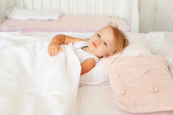 Niña durmiendo en la cama en el dormitorio con corona. Fiesta de cumpleaños princesa . — Foto de Stock