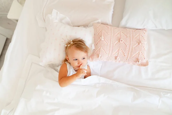 Niña durmiendo en la cama en el dormitorio con corona. Fiesta de cumpleaños princesa . — Foto de Stock