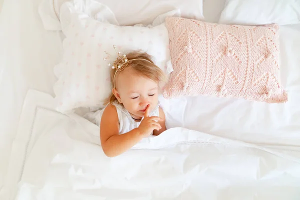 Niña durmiendo en la cama en el dormitorio con corona. Fiesta de cumpleaños princesa . — Foto de Stock