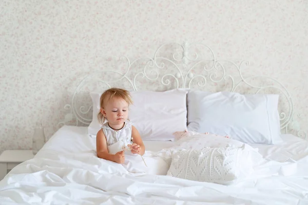 Niña sentada en la cama en el dormitorio con corona. Fiesta de cumpleaños princesa . — Foto de Stock