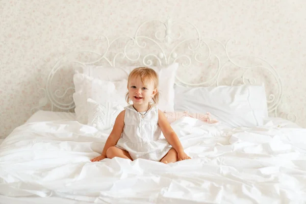小女孩躺在床上笑着。快乐的童年. — 图库照片