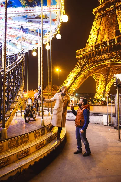 Amantes cerca de la Torre Eiffel y la noche de carruseles en París . — Foto de Stock