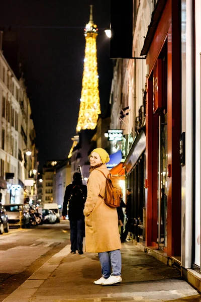 Mujer en gabardina con mochila caminando por la noche Paris . — Foto de Stock