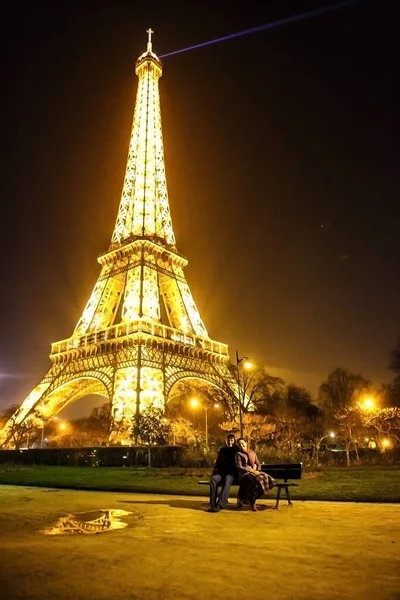 Любовники сидят на скамейке возле Эйфелевой башни ночью в Париже . — стоковое фото