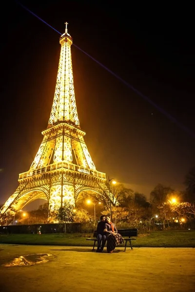 Kochankowie siedzieć na ławce w pobliżu Wieży Eiffla noc w Paryżu. — Zdjęcie stockowe