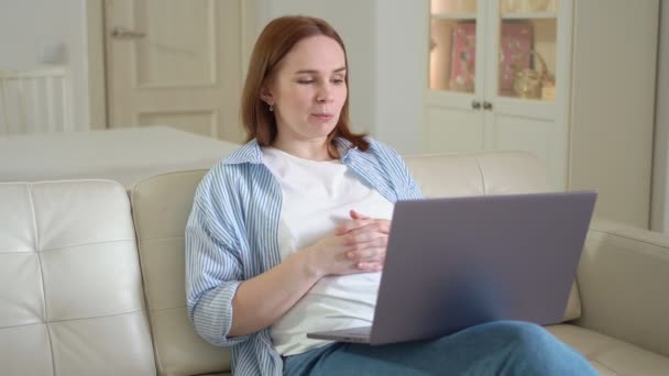 Женщина в прямом эфире или учебник на ноутбуке сидит на диване. удаленная работа . — стоковое видео