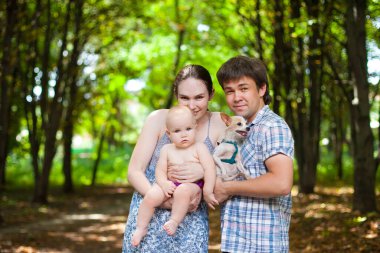 Kareli tişörtlü, küçük kızlı ve köpekli bir aile. doğada.