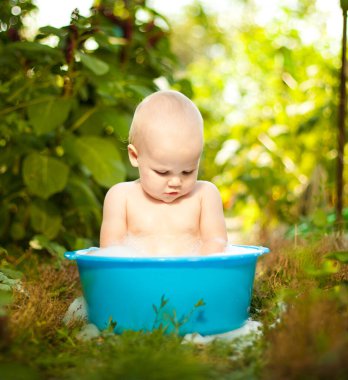 Bebek yaz bahçesindeki bir havuzda yıkanır. Sıcaktan korunmuş. 