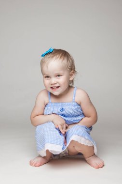 Mavi elbiseli, kısa saçlı küçük bir kız çocuğu. Mutlu çocukluk.