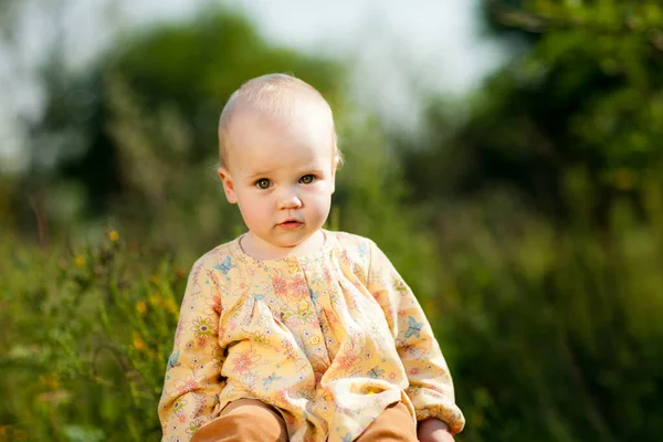 Baby auf dem Feld sitzend. Spaziergänge in der Natur mit Kindern. — Stockfoto