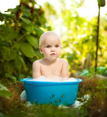 Bebek yaz bahçesindeki bir havuzda yıkanır. Sıcaktan korunmuş. 