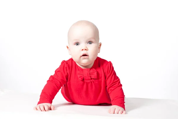 Baby girl in red dress lies on white background. child development and care. — Stock Photo, Image