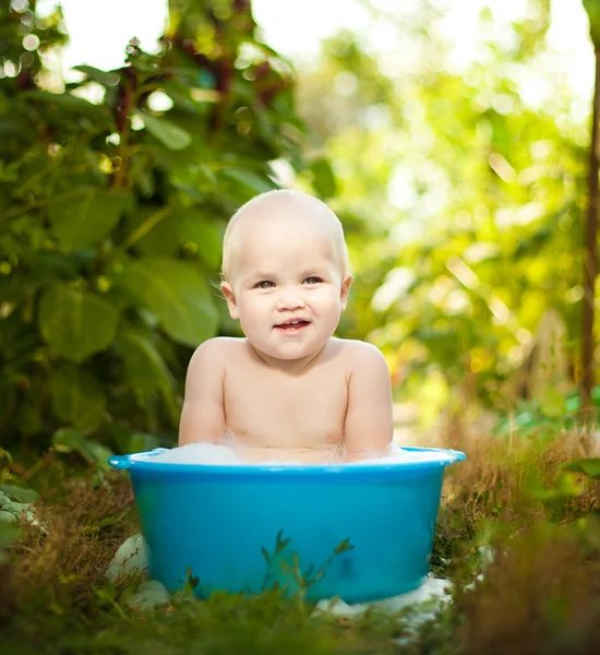 Barnet badar i ett handfat i sommarträdgården. sparas från värmen. — Stockfoto