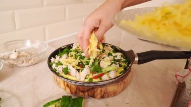 Yakın plan. Pizza tavada pişirilir ve rendelenmiş peynir serpiştirilir..