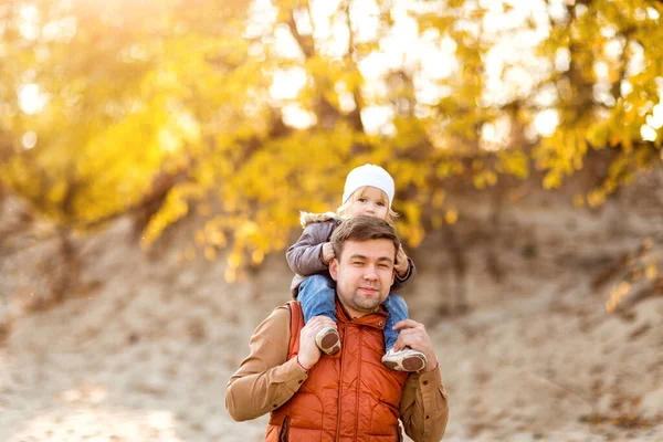 Menina sentada nos ombros do pai no passeio no outono. fim de semana familiar na natureza . — Fotografia de Stock