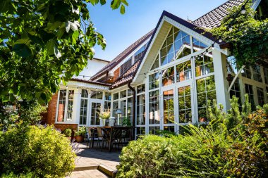 Panoramik pencereli beyaz yazlık ev. Bahçede ve kır evindeki masada..