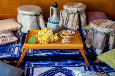 Doğuya. Üzüm ve sürahi ile küçük bir masa. geleneksel tekstil.