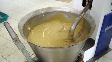 Şekerleme fabrikası. Halva hazırlamak için sıvı bileşenler karıştırılıyor.