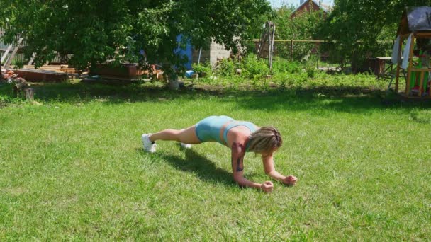 Tablón de ejercicios, soporte de manos. rubia chica con tatuajes juega deportes en jardín . — Vídeos de Stock