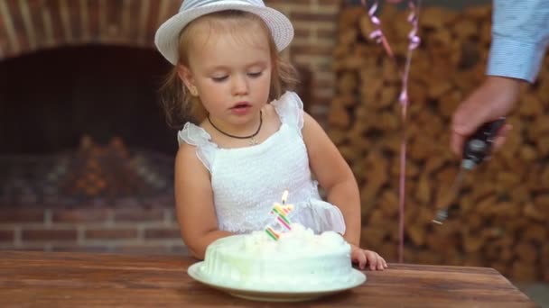 Bambina col cappello bianco che spegne la candela, numero tre sulla torta. — Video Stock