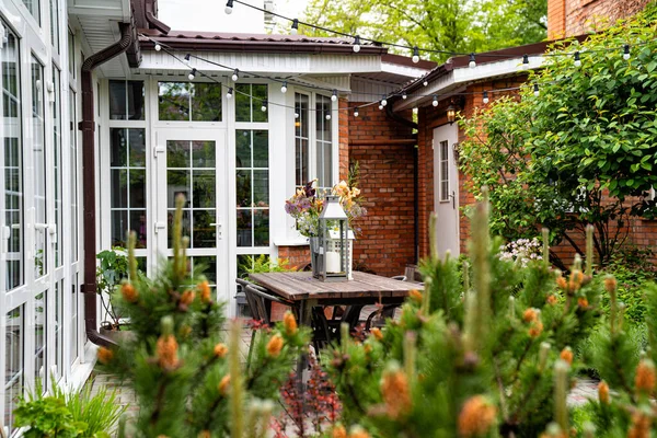 Stół w ogrodzie wiejskiego domu. świeczniki i bukiet kwiatów. — Zdjęcie stockowe