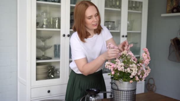 Frau reißt trockene und welke Blumen aus Strauß auf Küchentisch. — Stockvideo