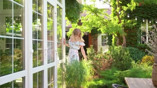 Hermosa chica rubia caminando en el jardín de verano en el patio trasero . — Vídeos de Stock