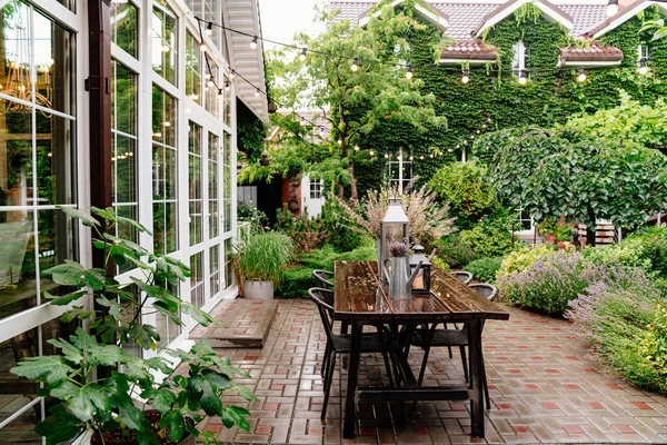 Bouquet of dried flowers and candles on table in yard in rain in summer. — Stock Photo, Image